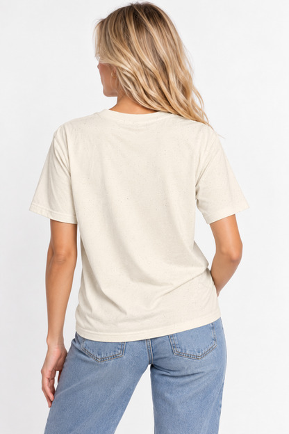 A woman viewed from the back wearing the CHIC by CHTQ Design Women’s Graphic T-Shirt in light beige with light blue jeans against a clean white studio background.