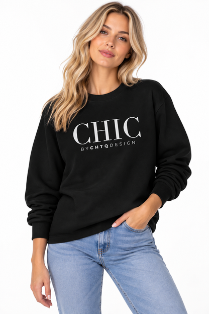 Woman wearing a black CHIC by CHTQ Design crewneck sweatshirt with a white graphic print, paired with light blue jeans against a white studio background.