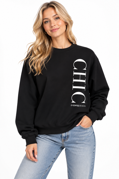 A woman wearing a black crewneck sweatshirt with a large vertical white 'CHIC' graphic and smaller 'BY CHTQ DESIGN' text, paired with light blue jeans against a plain white background.