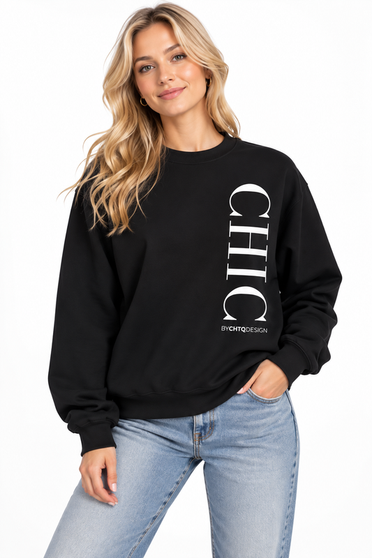 A woman wearing a black crewneck sweatshirt with a large vertical white 'CHIC' graphic and smaller 'BY CHTQ DESIGN' text, paired with light blue jeans against a plain white background.