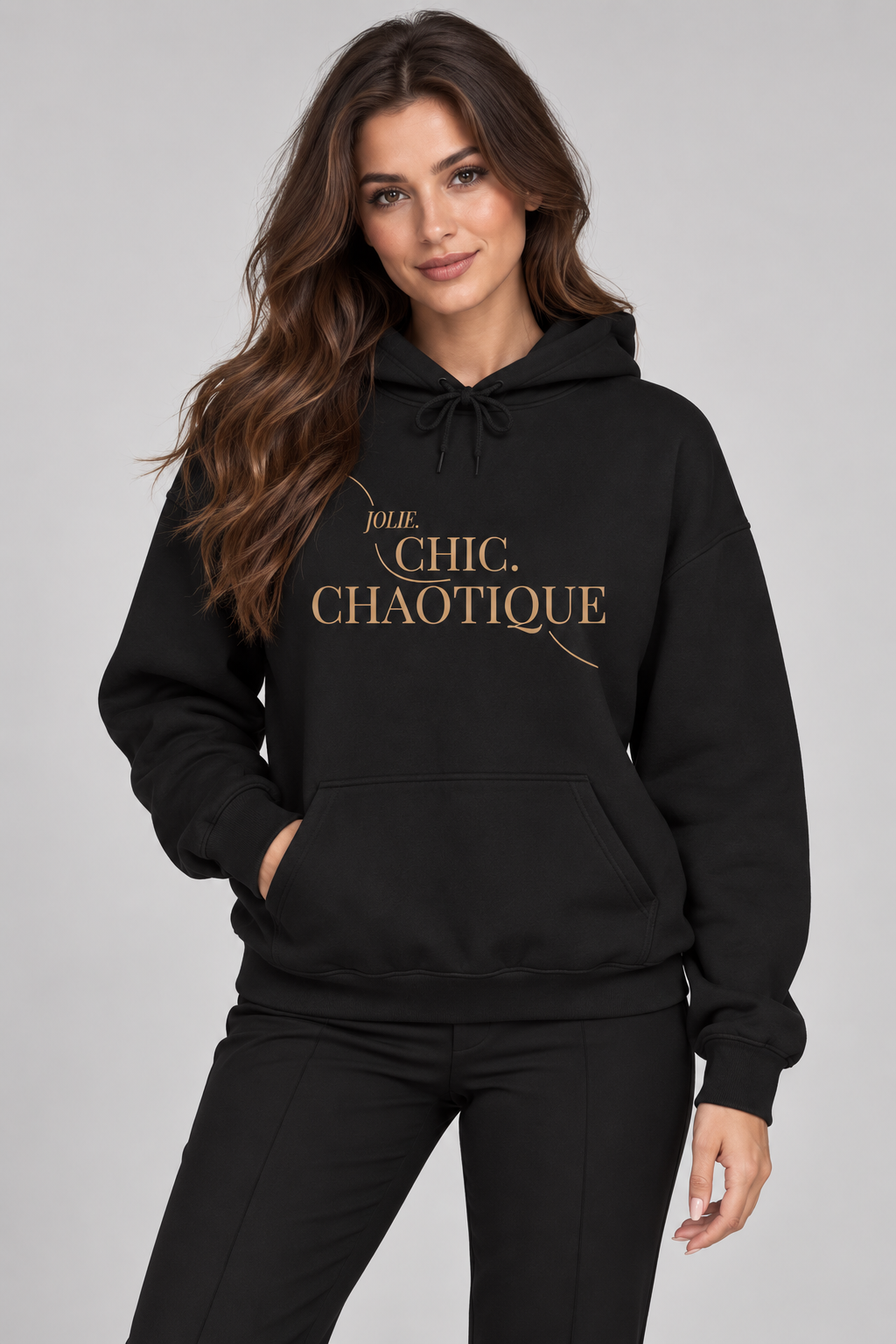 A woman modeling a black pullover hoodie with the phrase 'Jolie Chic. Chaotique.