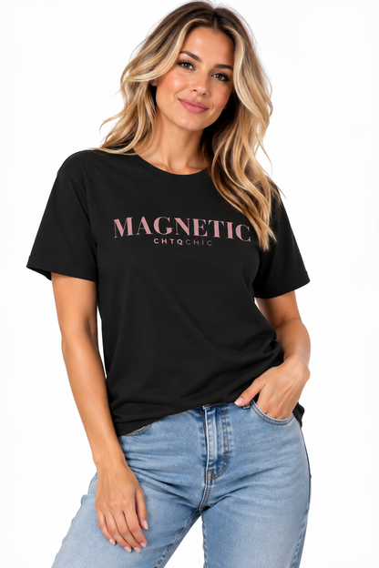 A woman wearing a black short-sleeve graphic T-shirt with 'MAGNETIC' and smaller 'CHTQ CHIC' text printed in pink across the chest, paired with light blue jeans, against a plain white background.