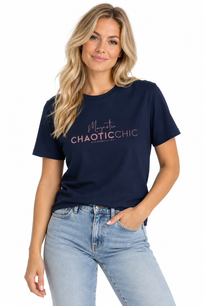 A woman modeling a navy blue short-sleeve graphic T-shirt with 'Magnetic Chaotic Chic' printed in pink and white on the chest, paired with light-wash blue jeans against a plain white background.