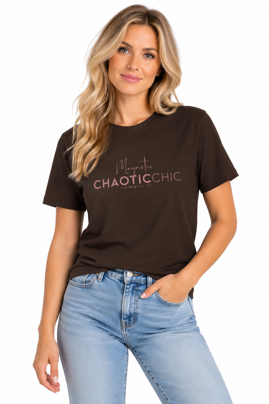 A woman modeling a dark brown short-sleeve graphic T-shirt with 'Magnetic Chaotic Chic' printed in pink across the chest, paired with light blue jeans against a plain white background.