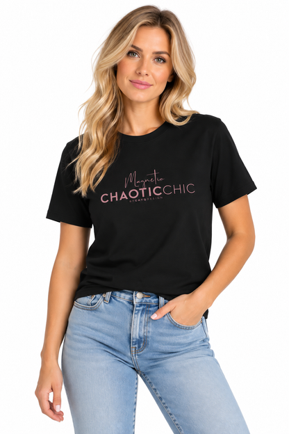 A woman modeling a black short-sleeve graphic T-shirt with pink text reading 'Magnetic Chaotic Chic', paired with light blue jeans against a plain white background.