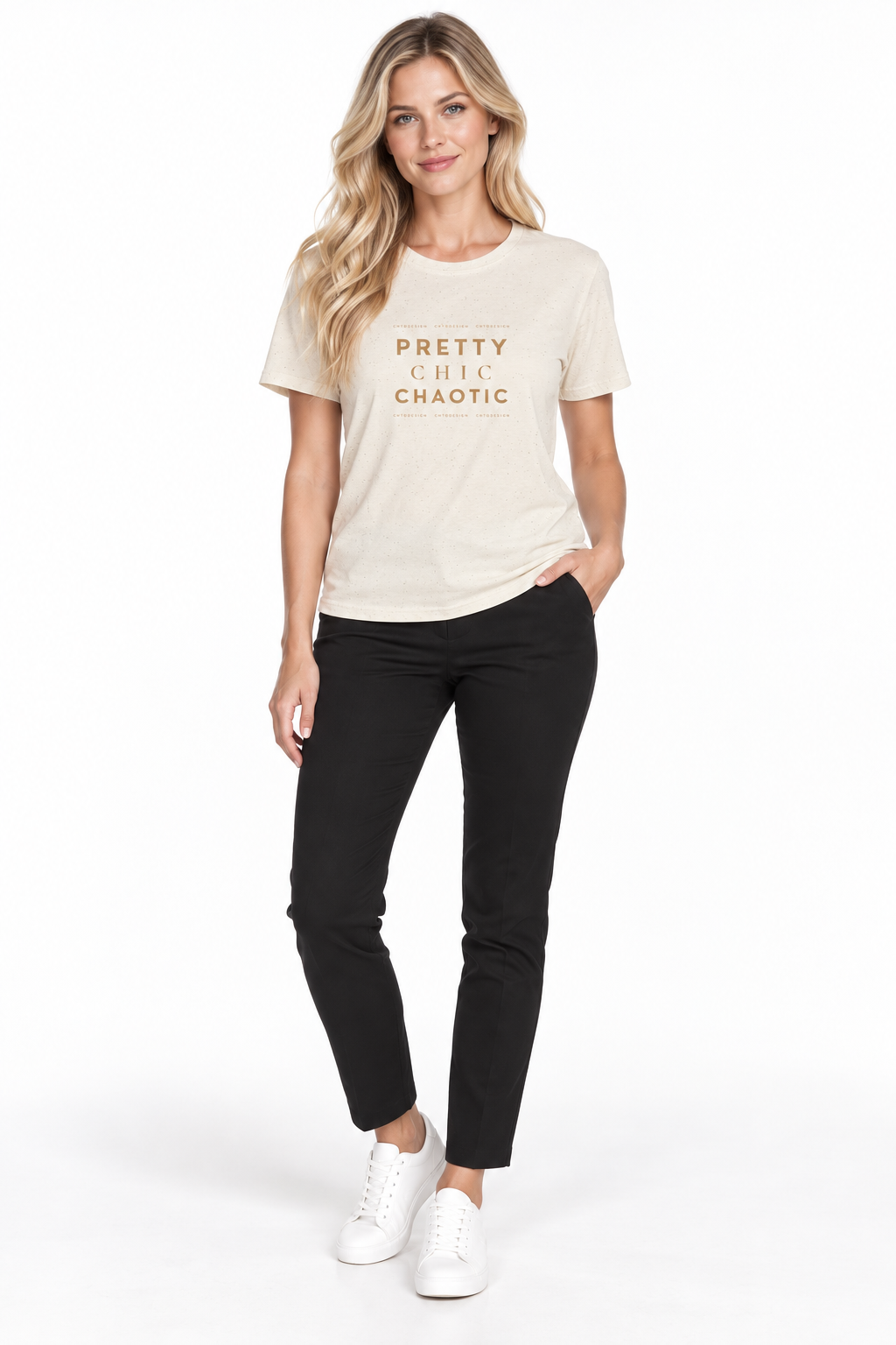 A woman modeling a beige graphic t-shirt with the words 'PRETTY CHIC CHAOTIC' printed in gold on the chest, paired with black pants and white sneakers against a white studio background.
