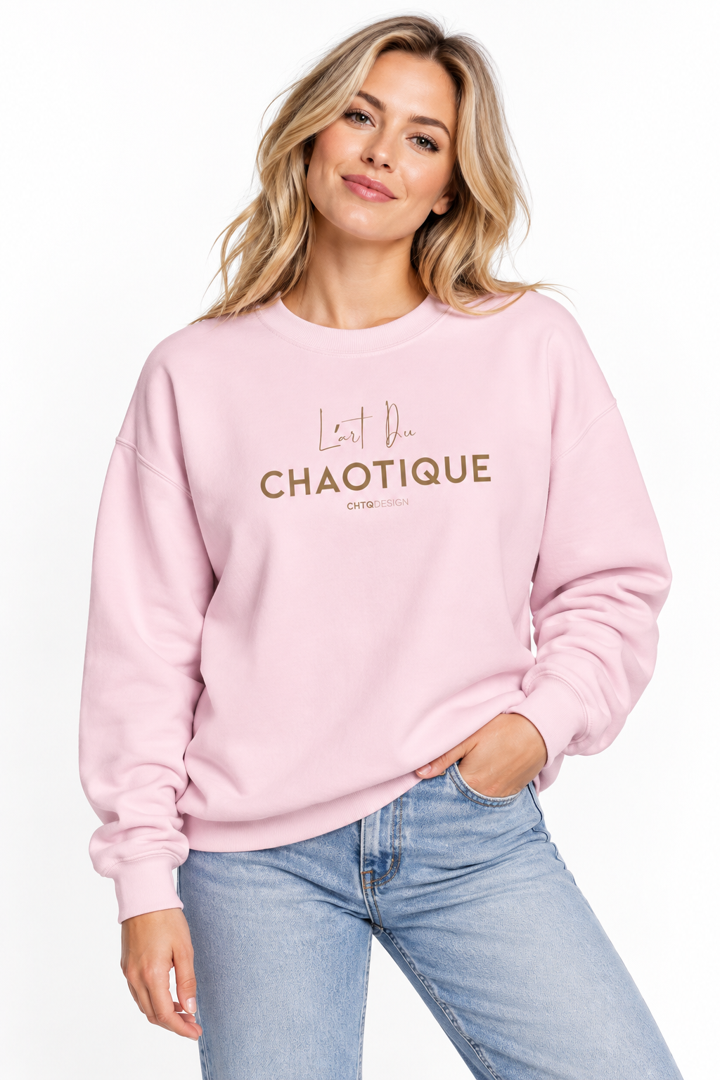 A woman wearing the light pink L’ART DU CHAOTIQUE crewneck sweatshirt with minimalist front typography, paired with light blue jeans against a clean white studio background.