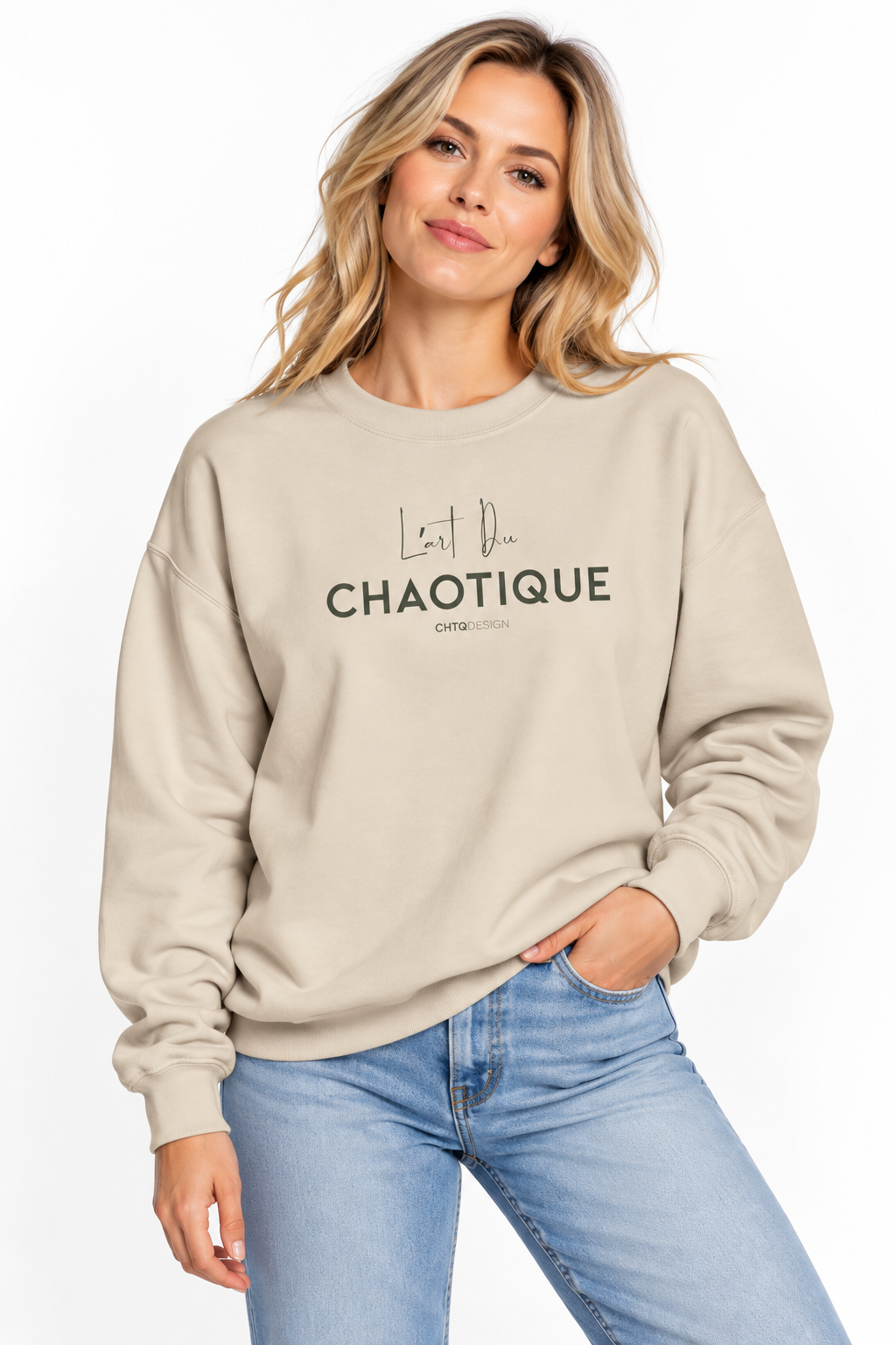 A woman wearing the beige L’ART DU CHAOTIQUE crewneck sweatshirt with minimalist front typography, paired with light blue jeans against a clean white studio background.