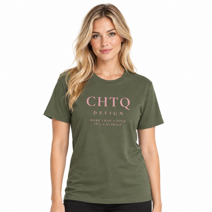 A woman modeling an military green crewneck T-shirt with pink “CHTQ DESIGN” and “MORE THAN A SHIRT, IT’S A MOVEMENT” text on the front, paired with black pants against a plain white background.