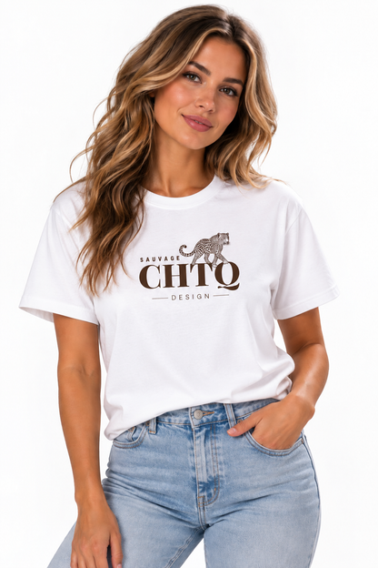 A woman wearing a white short-sleeve graphic T-shirt with a brown cheetah and the text 'SAUVAGE CHTQ DESIGN' on the front, paired with light blue jeans, against a plain white background.