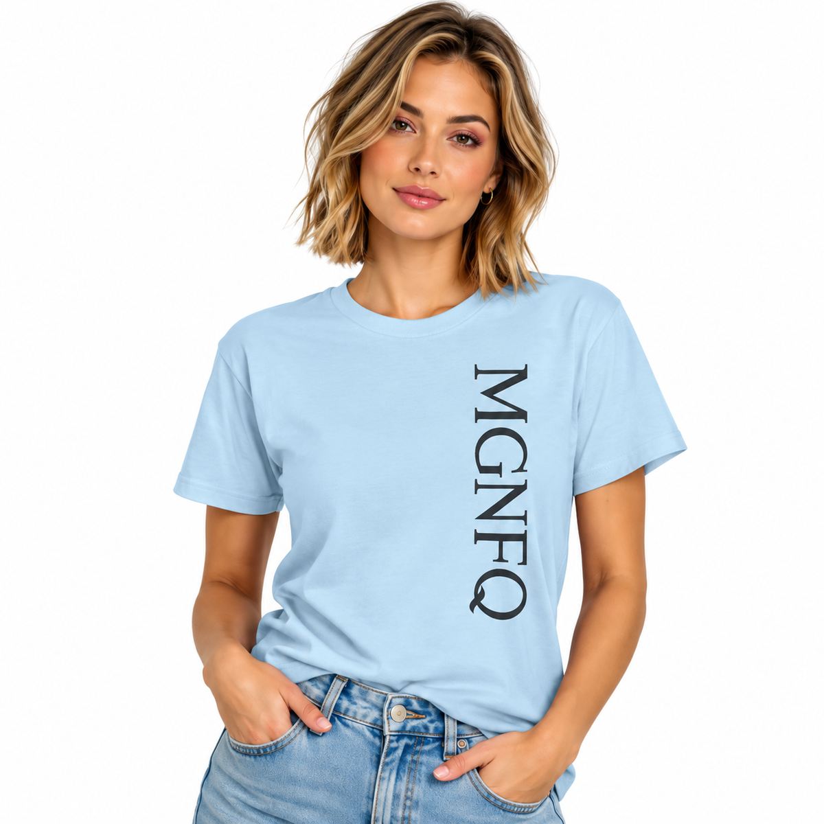A woman wearing a light blue short-sleeve T-shirt with “MGNFQ” printed vertically in white on the front, paired with light blue jeans against a plain white studio background.