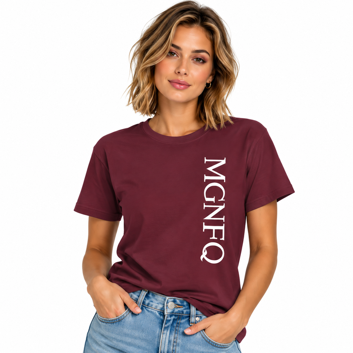 A woman wearing a maroon short-sleeve T-shirt with “MGNFQ” printed vertically in white on the front, paired with light blue jeans against a plain white studio background.