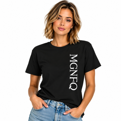 A woman wearing a black short-sleeve T-shirt with “MGNFQ” printed vertically in white on the front, paired with light blue jeans against a plain white studio background.