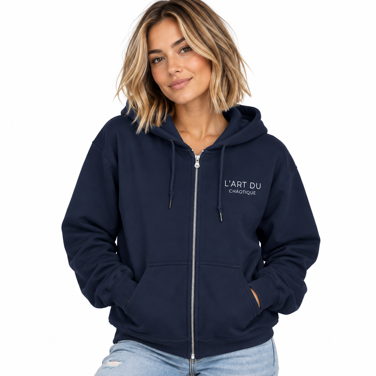 Woman modeling a navy CHTQ Design zip-up hoodie with a white L’Art du Chaotique graphic on the left chest against a white studio background.