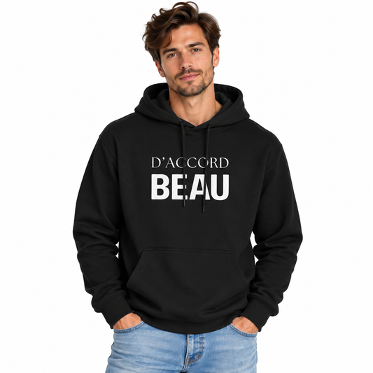 A man wearing a black pullover hoodie with the French text 'D'ACCORD BEAU' printed in white across the chest, paired with light blue jeans, set against a plain white background.