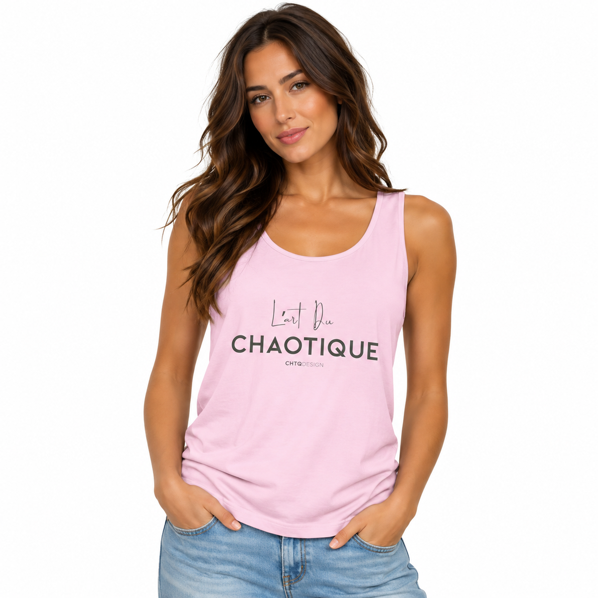A woman modeling a light pink sleeveless tank top with black text reading 'L'Art Du CHAOTIQUE' on the front, paired with light blue jeans against a plain white background.