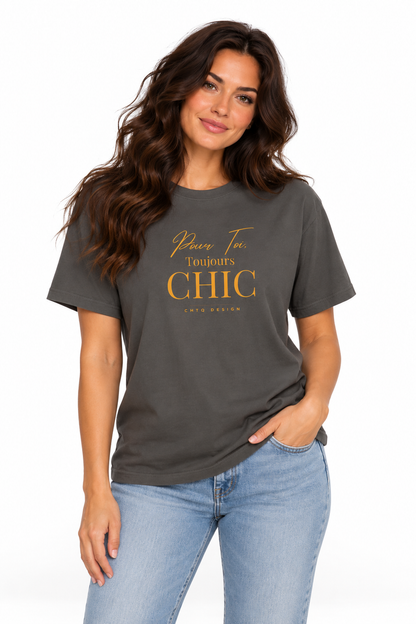 A woman modeling a dark charcoal gray t-shirt with gold text that reads 'Pour Toi Toujours CHIC' and 'CHTQ Design', paired with light blue jeans against a plain white background.