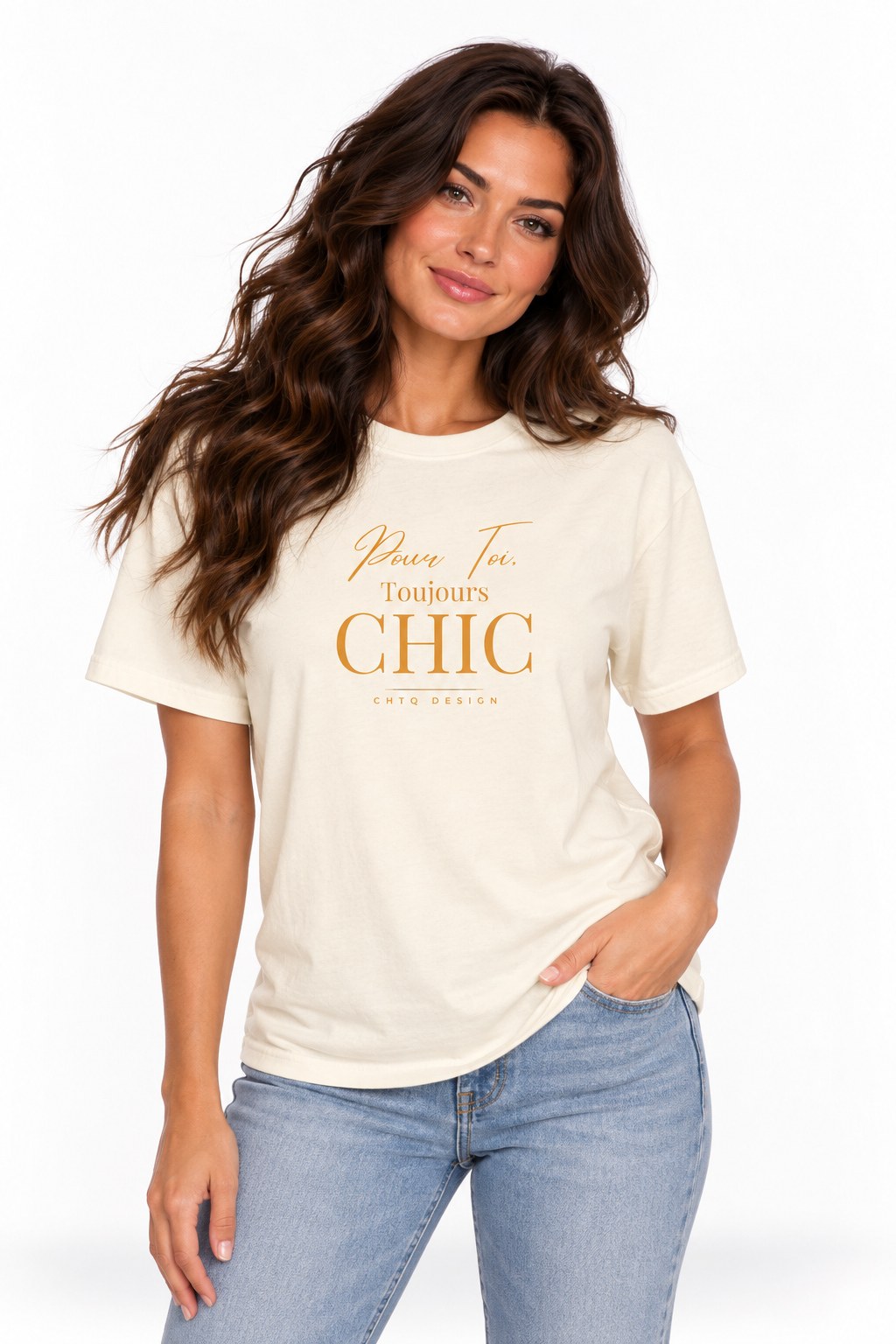 A woman with long wavy brown hair models a cream-colored graphic t-shirt with gold lettering that reads 'Pour Toi, Toujours CHIC' and 'CHTQ Design'. She is wearing light wash blue jeans against a clean white background.