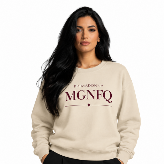 A woman with long black hair wearing a cream-colored crewneck sweatshirt with 'PRIMADONNA MGNFQ' printed in dark red on the chest, paired with black pants, against a plain white background.