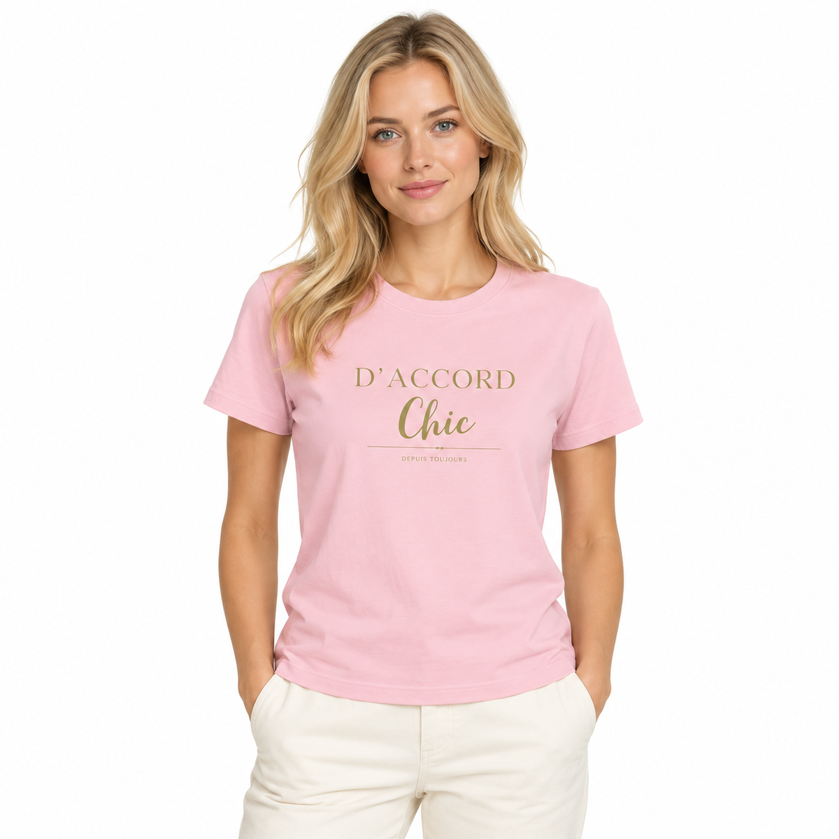 A woman wearing a light pink crewneck t-shirt with 'D'ACCORD Chic' printed in gold lettering on the chest, paired with off-white pants, set against a plain white background.