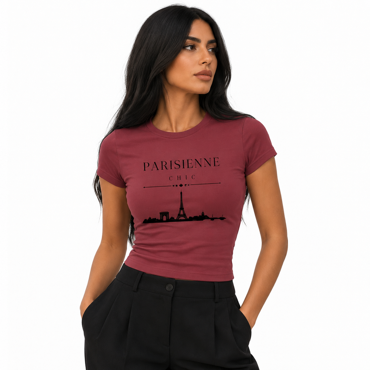 A woman modeling a fitted short-sleeve crewneck t-shirt in dusty rose with a black graphic print of the Eiffel Tower and the text 'PARISIENNE CHIC'. She is wearing black trousers against a clean white background.