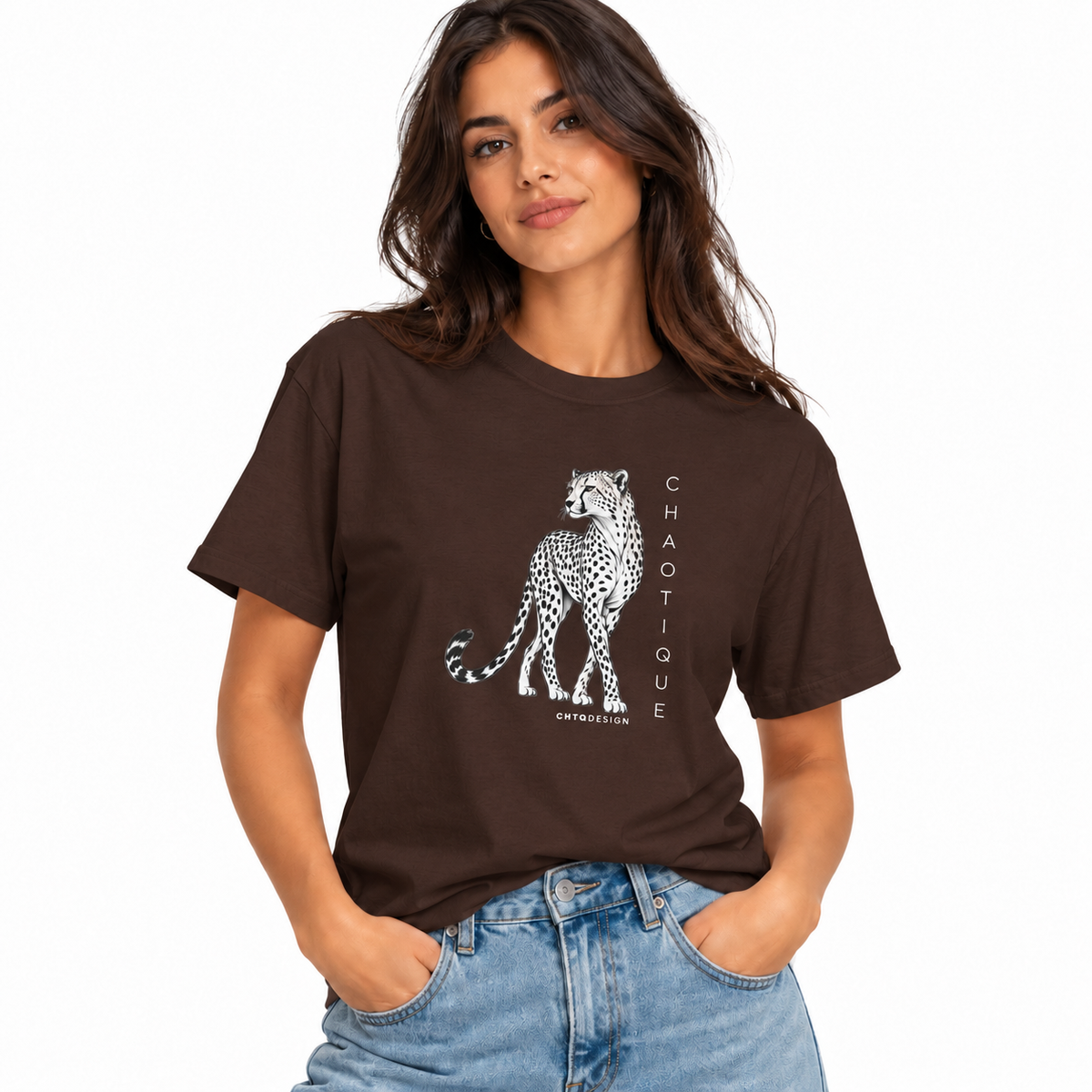 Woman wearing a dark chocolate brown CHAOTIQUE graphic T-shirt with hand-drawn cheetah illustration and vertical CHAOTIQUE text, styled with light blue jeans.