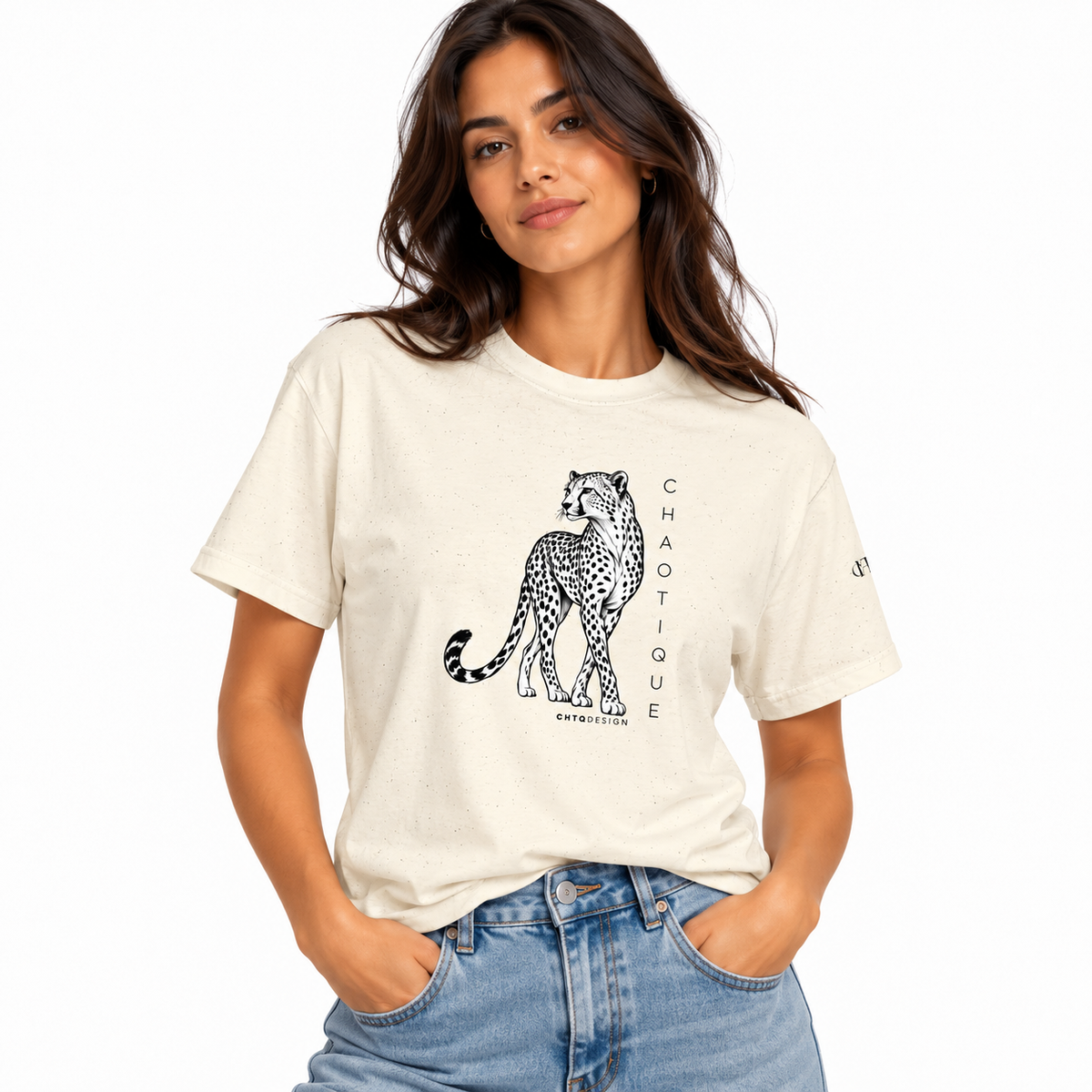 Woman wearing a natural CHAOTIQUE graphic T-shirt with hand-drawn cheetah illustration and vertical CHAOTIQUE text, styled with light blue jeans.