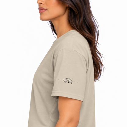 Close-up of sand CHAOTIQUE graphic T-shirt sleeve featuring a small CHTQ Design logo.