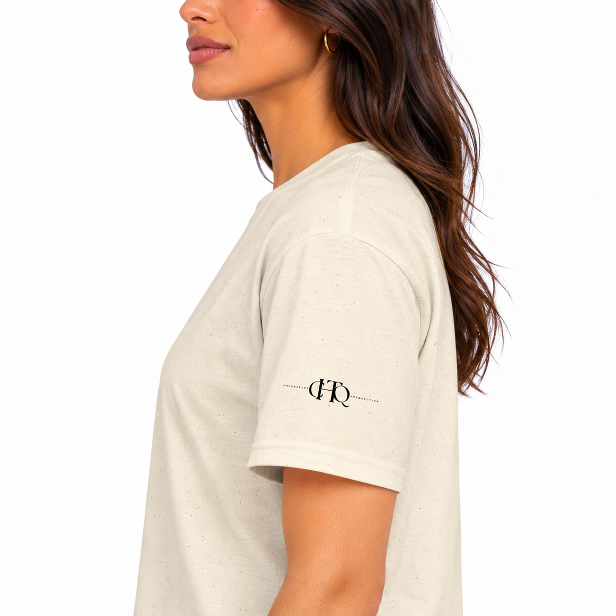 Close-up of natural CHAOTIQUE graphic T-shirt sleeve featuring a small CHTQ Design logo.