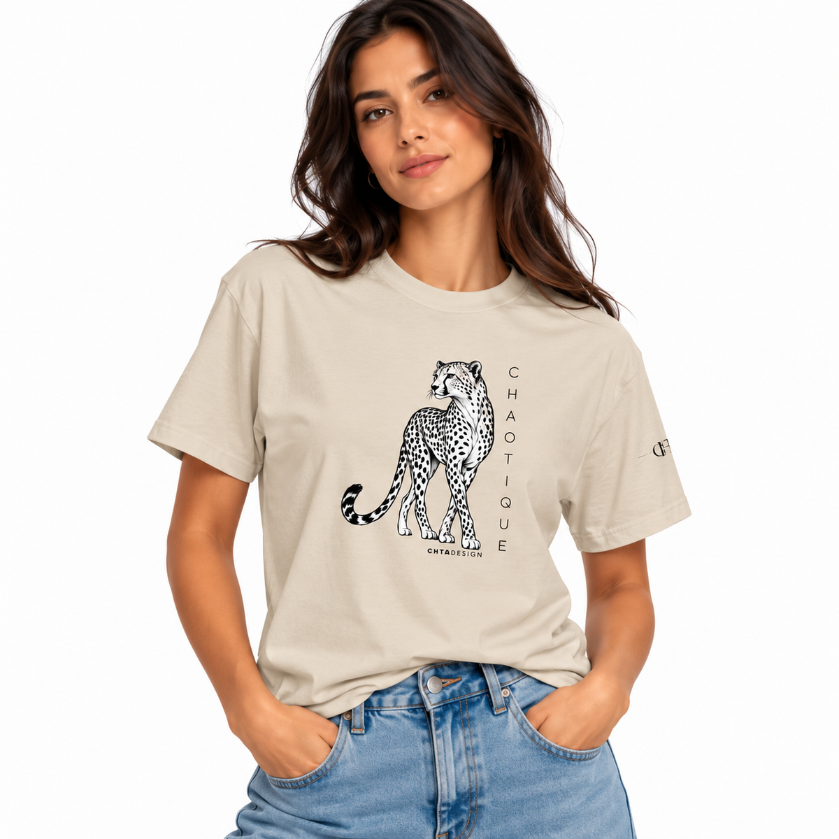 Woman wearing a sand CHAOTIQUE graphic T-shirt with hand-drawn cheetah illustration and vertical CHAOTIQUE text, styled with light blue jeans.
