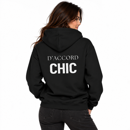 A woman shown from the back wearing a black hoodie with 'D'ACCORD CHIC' printed in white across the back, paired with dark gray jeans, against a plain white background.