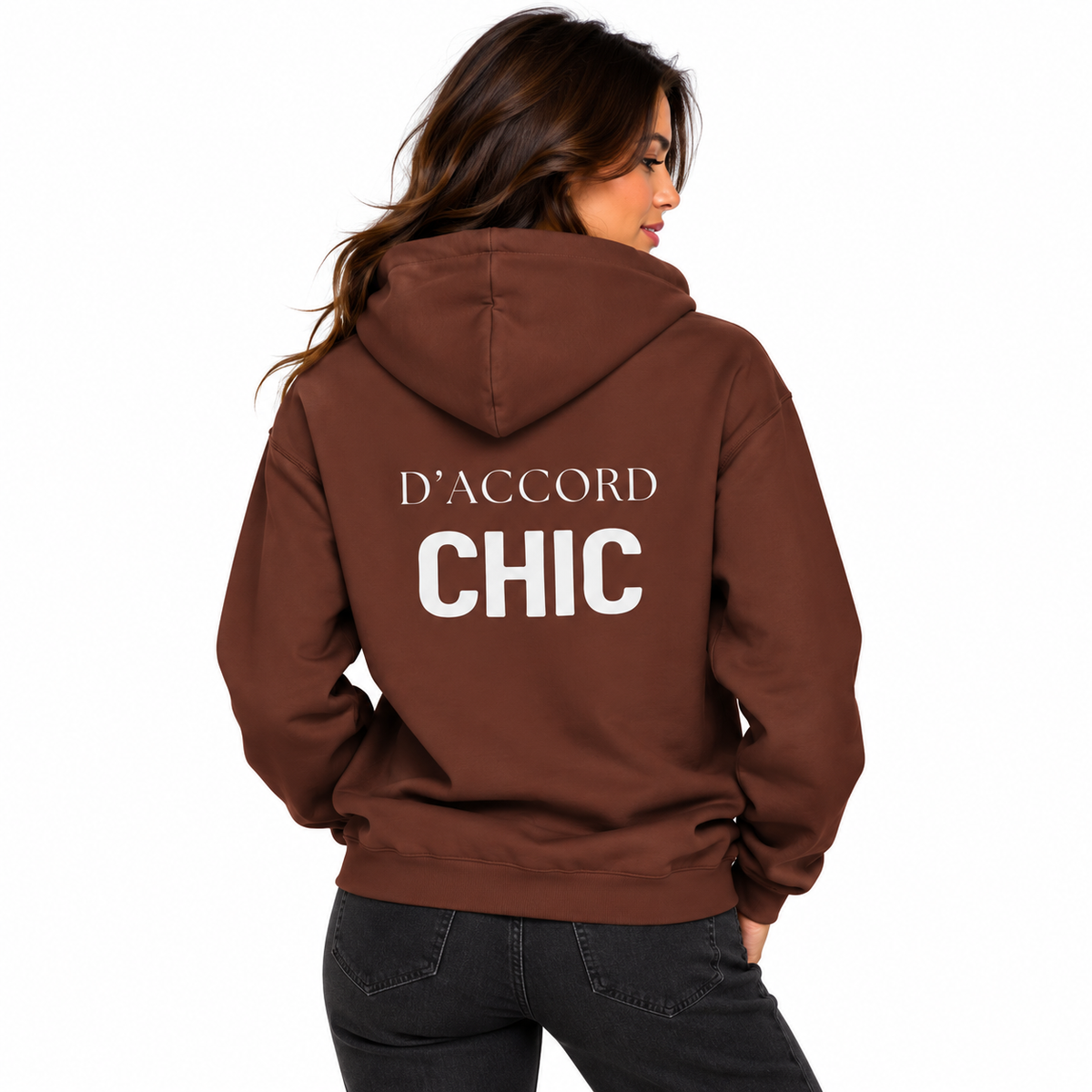 A woman shown from the back wearing a brown hoodie with the words 'D'ACCORD CHIC' printed in white across the back, paired with dark jeans against a plain white background.