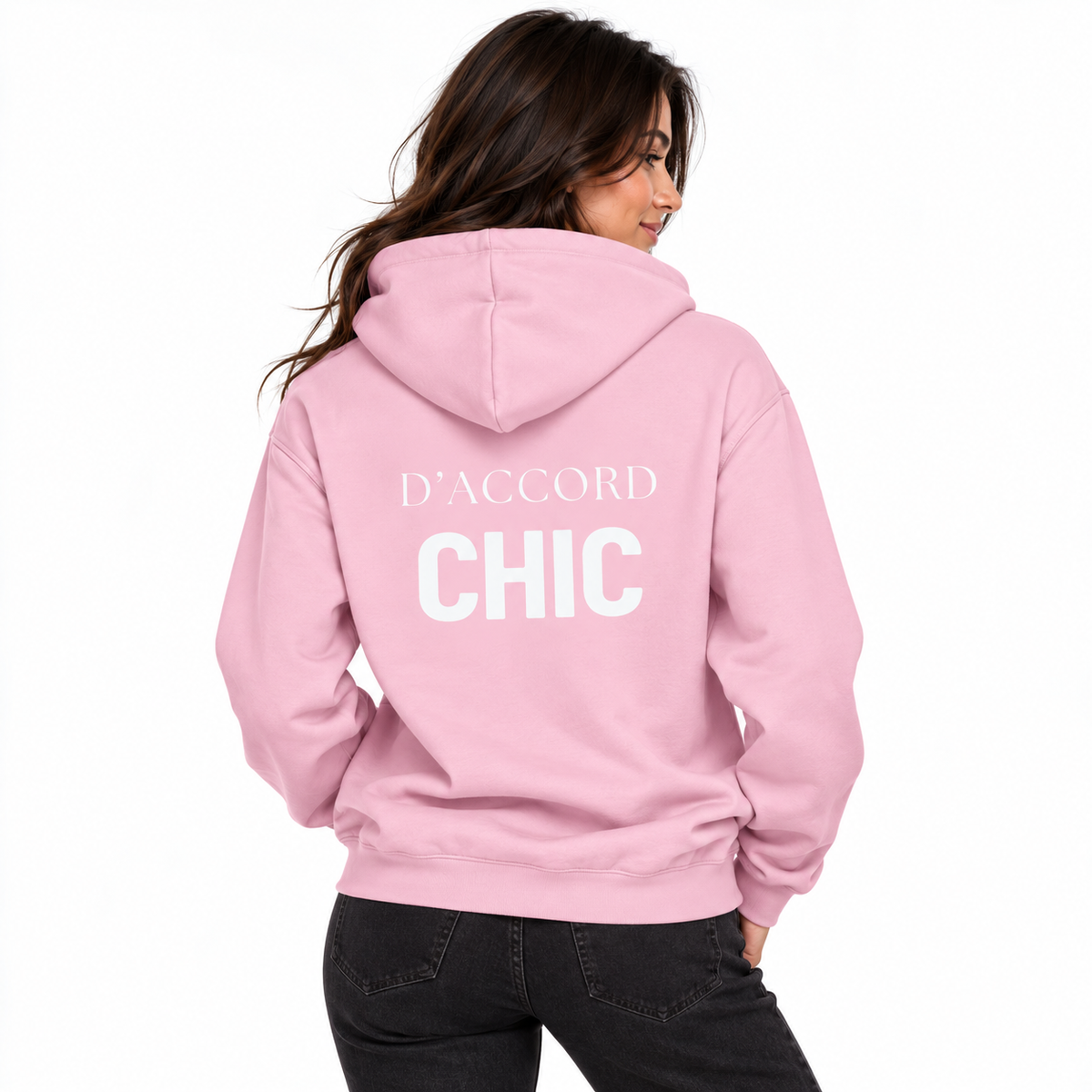A woman shown from the back wearing a light pink hoodie with 'D'ACCORD CHIC' printed in white across the back, paired with black jeans against a plain white background.