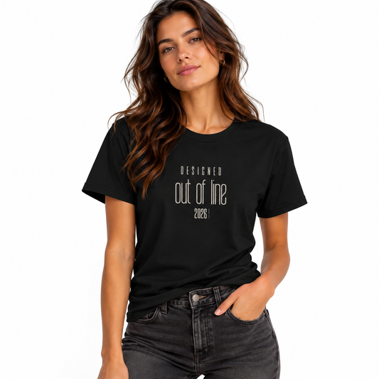 Female model wearing a black Designed Out of Line 2026 graphic T-shirt with dark washed jeans against a white studio background.