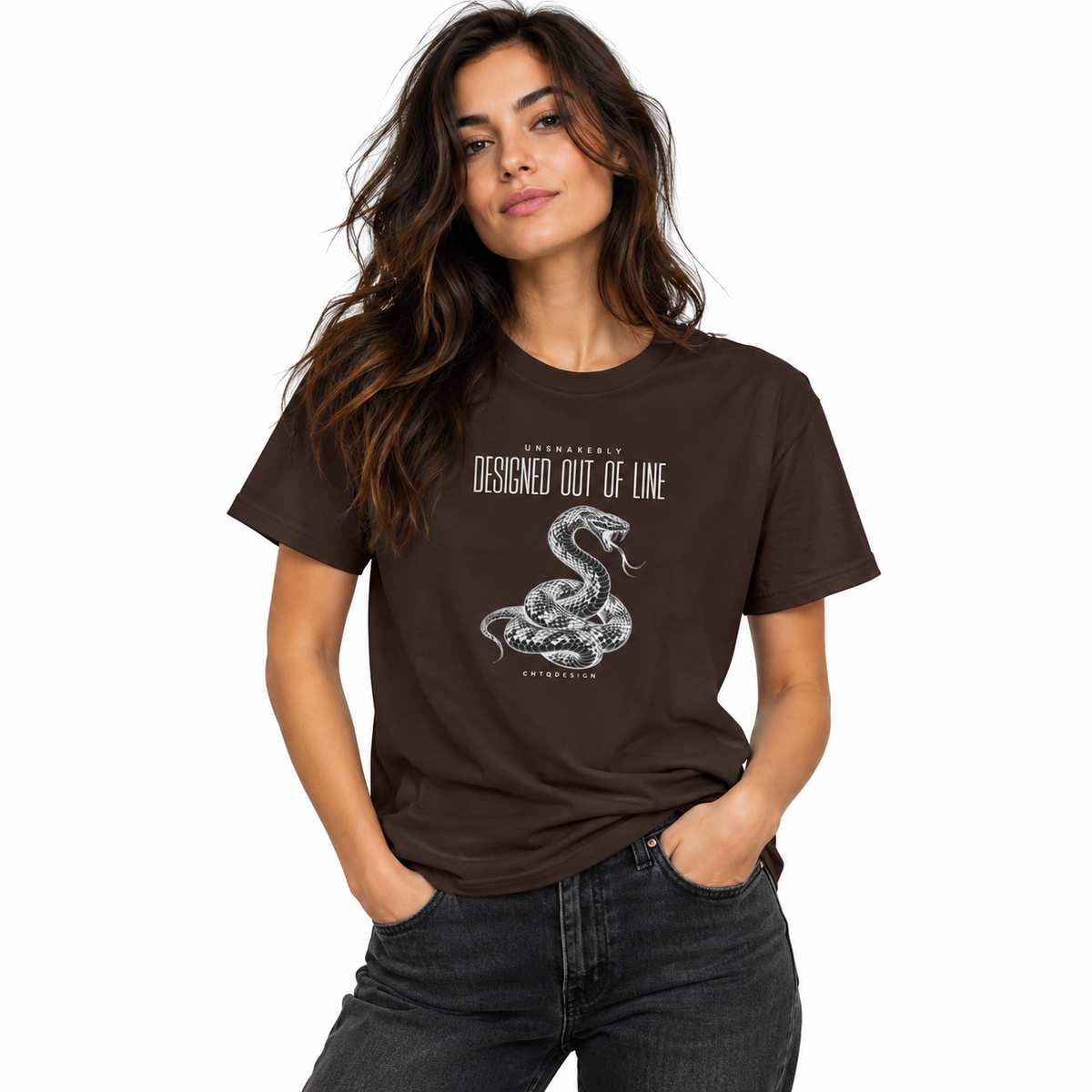 Female model wearing a chocolate brown UNSNAKEBLY snake graphic T-shirt with dark jeans against a white studio background.