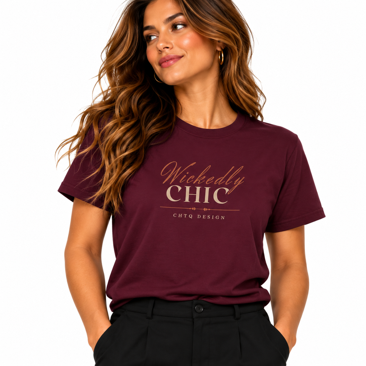 A woman wearing a maroon short-sleeve graphic t-shirt with 'Wickedly CHIC' printed in gold on the front, paired with black pants, against a solid white background.