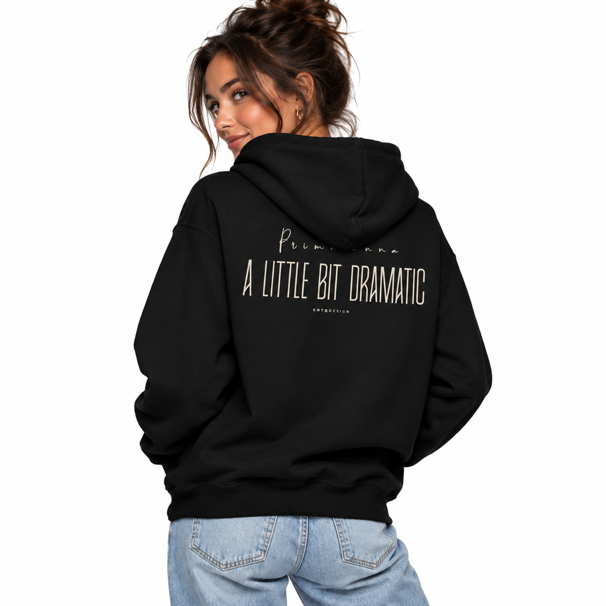 A woman shown from the back wearing a black hoodie with the text 'Primadonna A LITTLE BIT DRAMATIC' printed in white on the back, paired with light blue jeans against a plain white background.