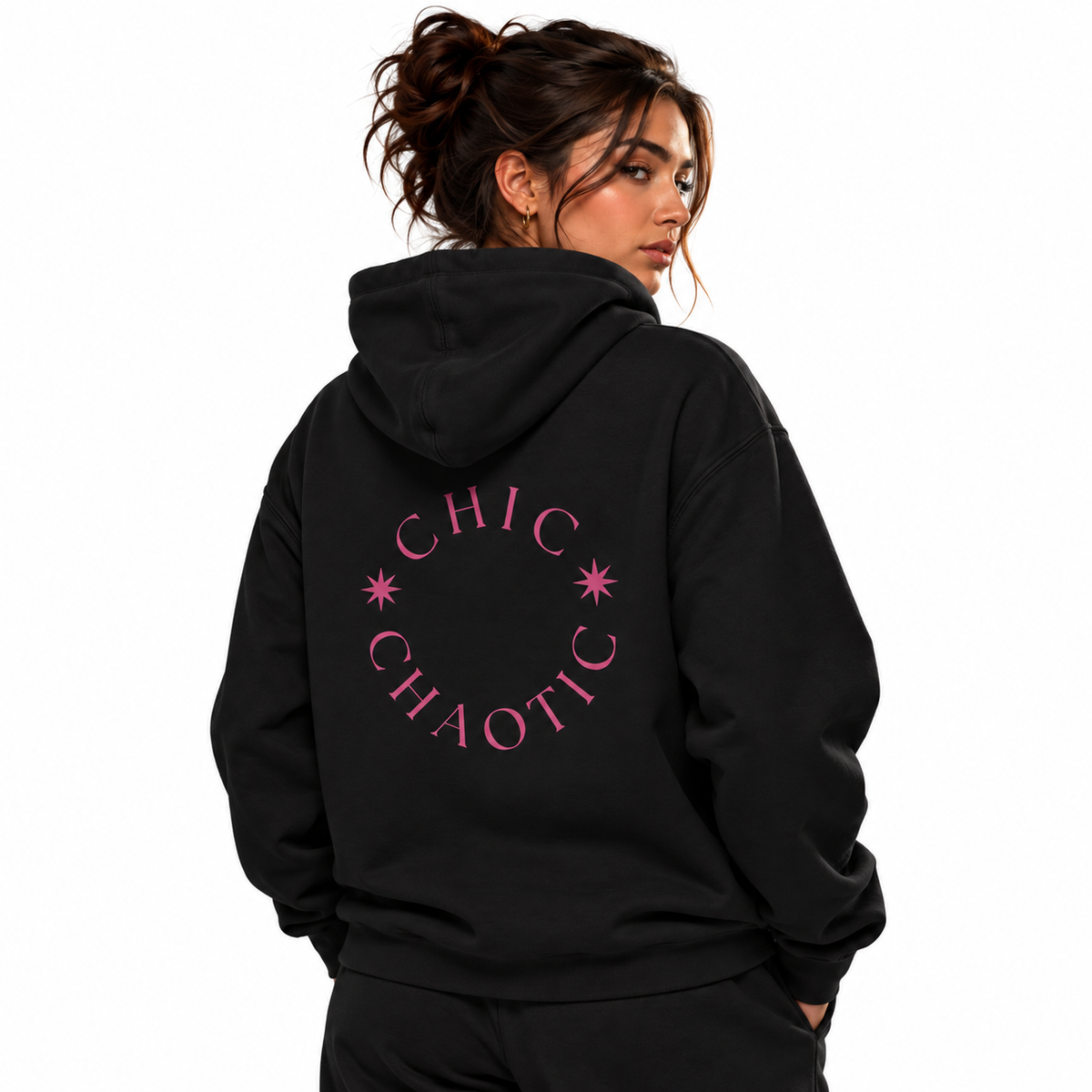 A woman wearing a black pullover hoodie with a pink circular graphic on the back that reads 'CHIC CHAOTIC' with small star accents, shown against a plain white background.