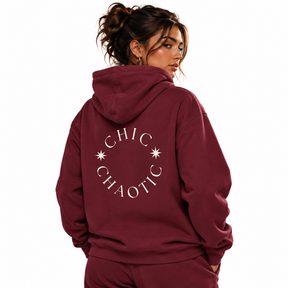 A woman shown from the back wearing a burgundy hoodie with a white circular graphic that reads 'CHIC CHAOTIC' and small star details, against a plain white background.