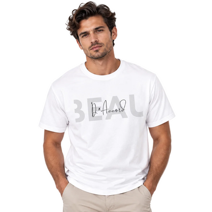 A man wearing a white crew-neck t-shirt with a gray graphic print on the front that reads 'BEAU' and 'D'Accord', paired with beige pants, against a plain white background.