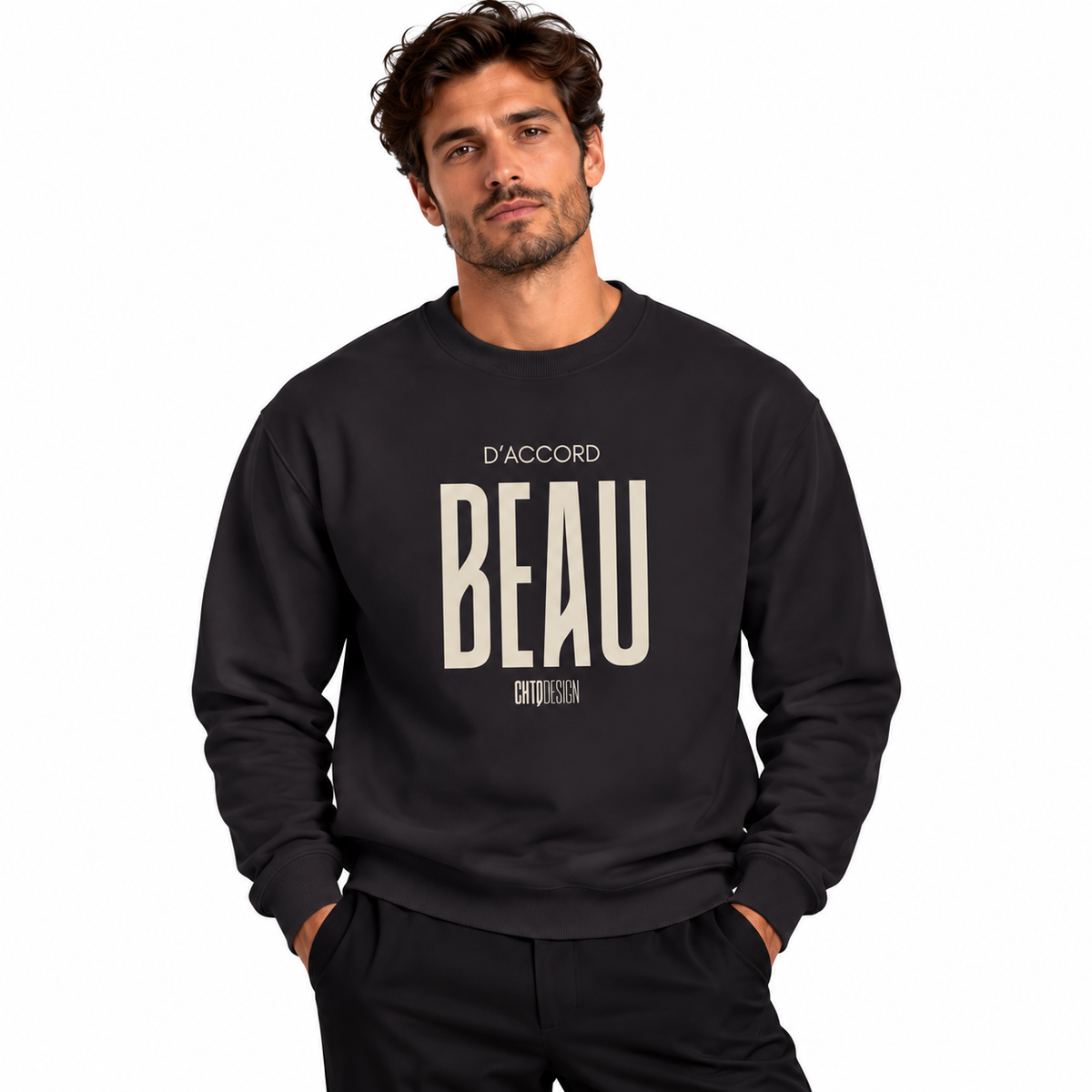 A man wearing a dark crewneck sweatshirt with a large cream-colored graphic print on the front that reads 'D'ACCORD BEAU ENTHUSIAST', posed against a solid white background.