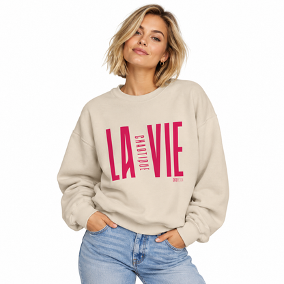 Woman wearing sand LA VIE CHAOTIQUE crewneck sweatshirt with vibrant magenta graphic
