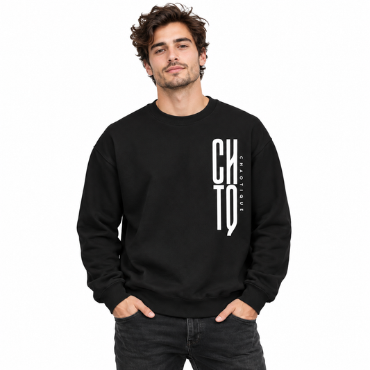 Male model wearing a black CHTQ CHAOTIQUE men's crewneck sweatshirt with a bold vertical white CHTQ graphic and CHAOTIQUE lettering, front view in a white studio.