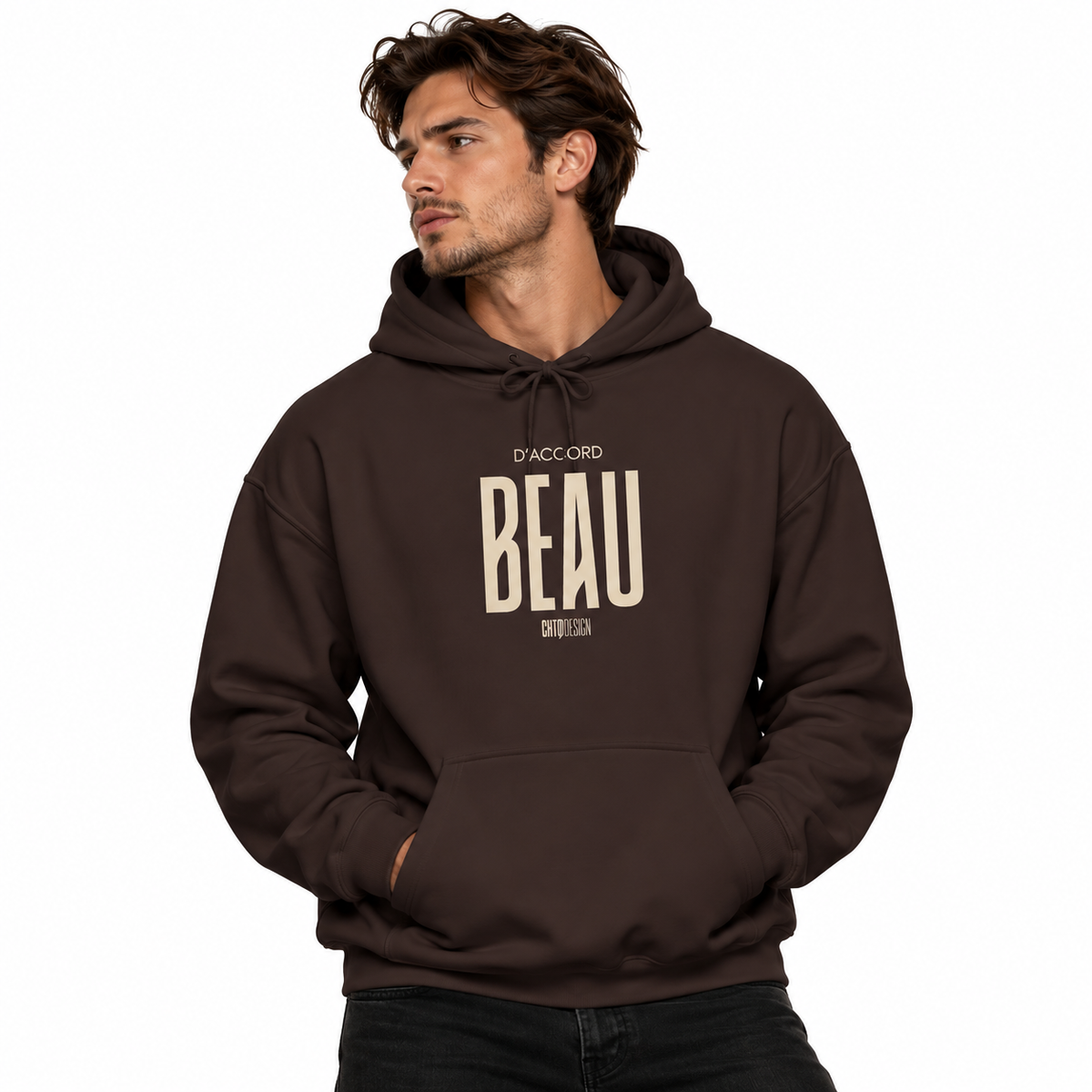 A man wearing a dark brown pullover hoodie with a beige graphic print on the chest that reads 'D'ACCORD BEAU' and, set against a plain white background.