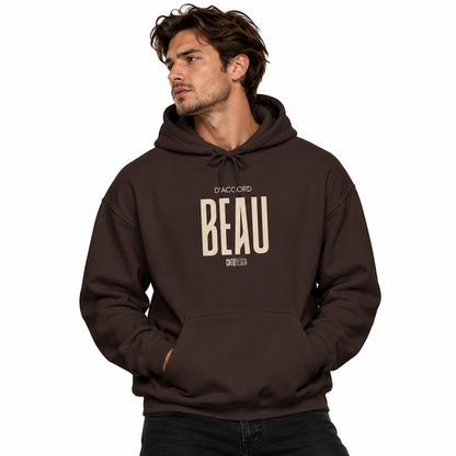 A man wearing a dark brown pullover hoodie with a beige graphic print on the chest that reads 'D'ACCORD BEAU' and, set against a plain white background.