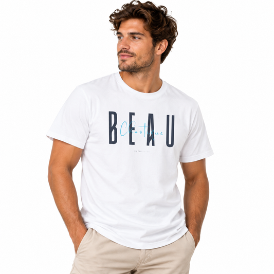 A man wearing a white crewneck t-shirt with a graphic print that reads 'BEAU chaotique' in navy and light blue, paired with beige pants, against a plain white background.