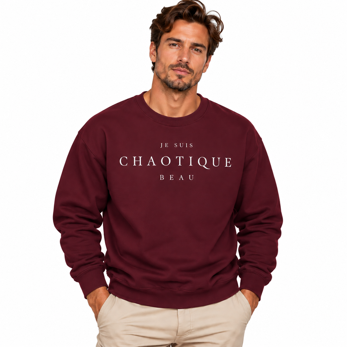 A man wearing a maroon crewneck sweatshirt with the text 'JE SUIS CHAOTIQUE BEAU' printed in white across the chest, paired with beige pants, set against a plain white background.