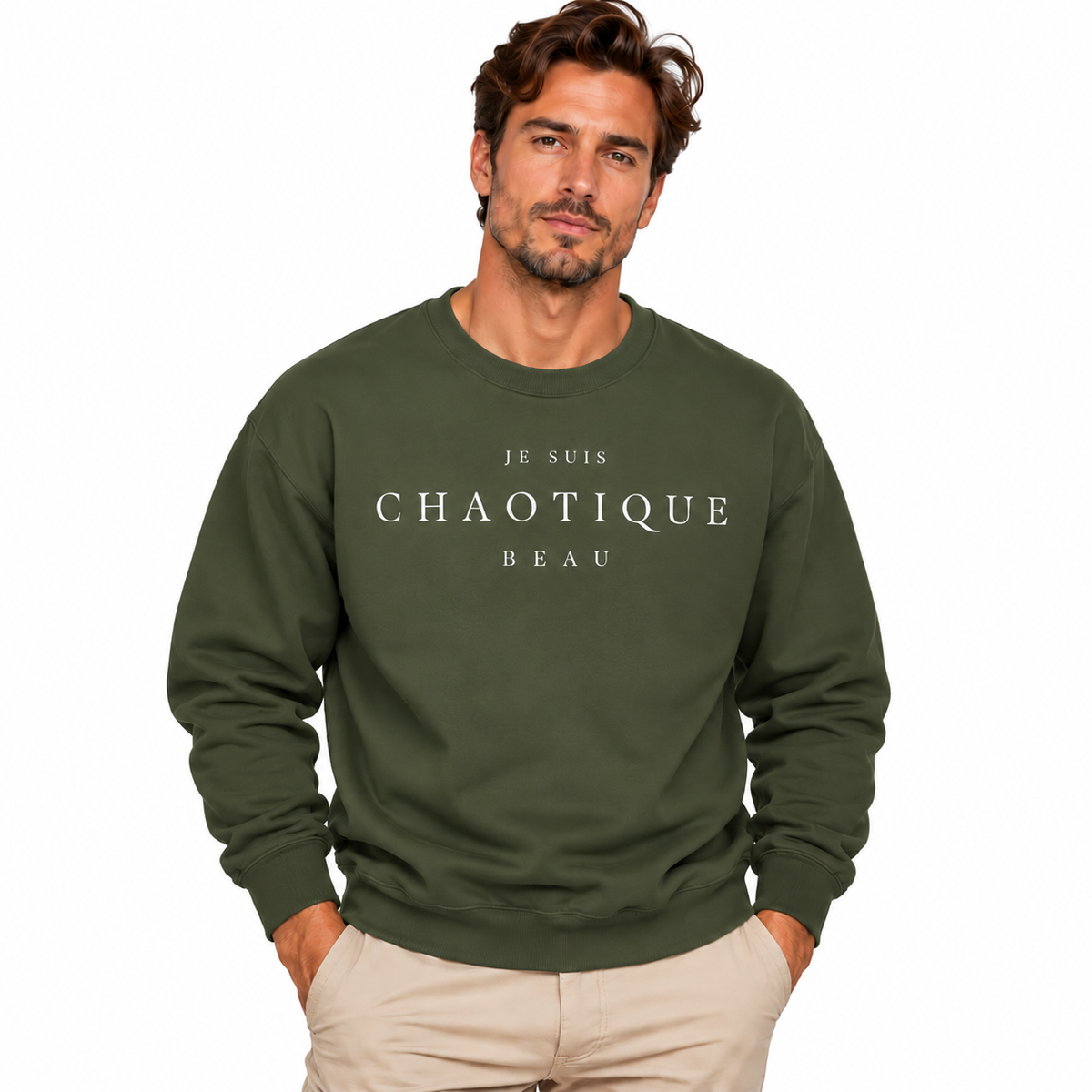 A man wearing a green crewneck sweatshirt with the text 'JE SUIS CHAOTIQUE BEAU' printed in white across the chest, paired with beige pants, set against a plain white background.