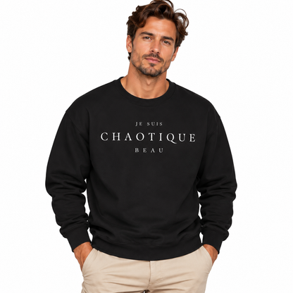 A man wearing a black crewneck sweatshirt with the text 'JE SUIS CHAOTIQUE BEAU' printed in white across the chest, paired with beige pants, set against a plain white background.