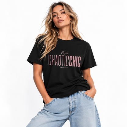 Blonde woman wearing a black Magnetic CHAOTICCHIC graphic T-shirt with dusty pink lettering and relaxed light blue jeans in a white studio.
